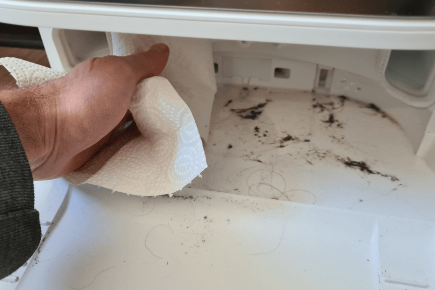 The dirt in the cleaning tray of the Dreame L10s Ultra base station is removed with a wipe.